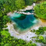 Vista aérea de la Olla de San Vicente en el río Dobra, una poza natural de aguas cristalinas y turquesas rodeada de un frondoso bosque cerca de Cangas de Onís.